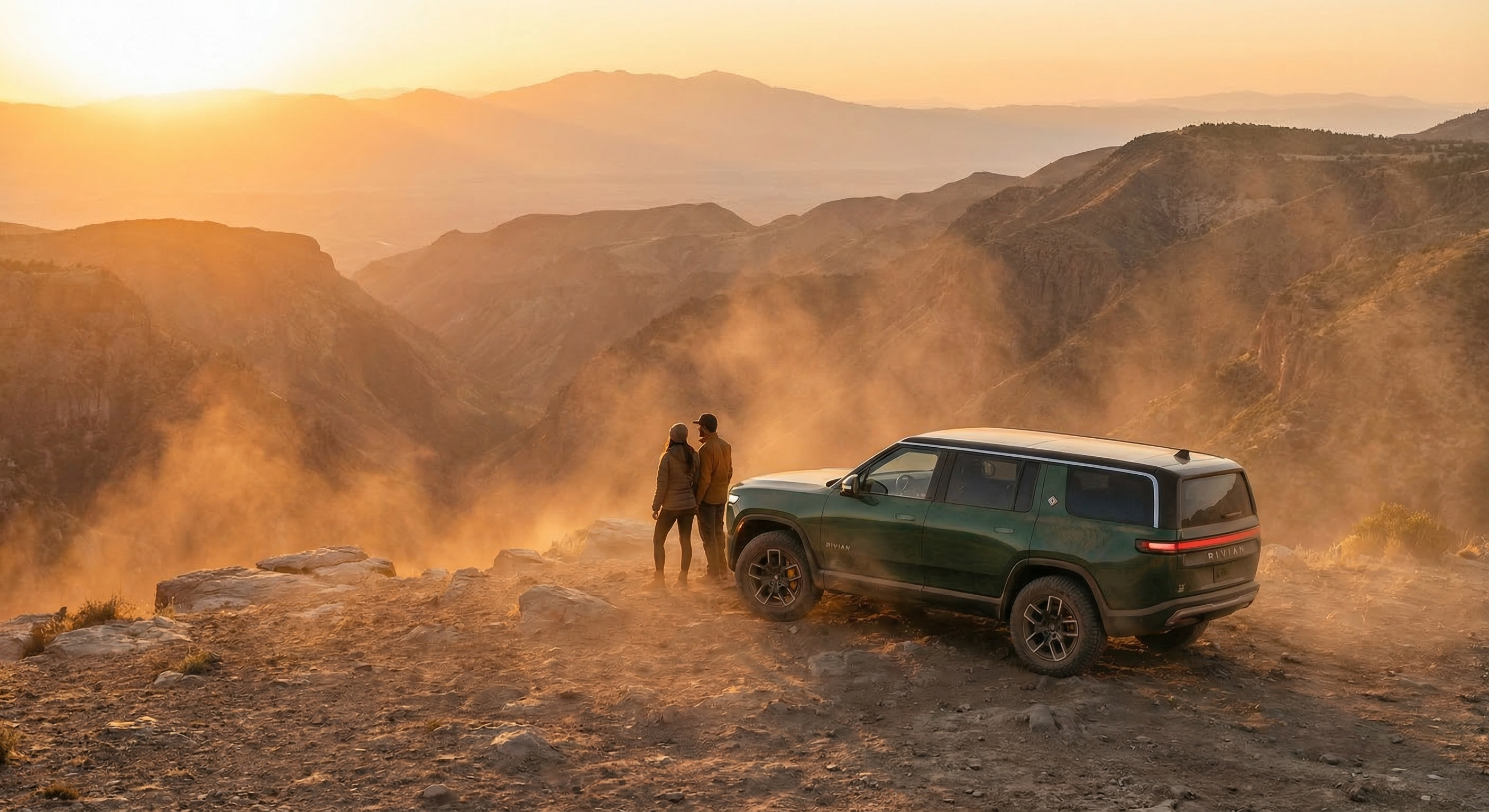 Rivian vehicle parked at a scenic mountain overlook during golden hour